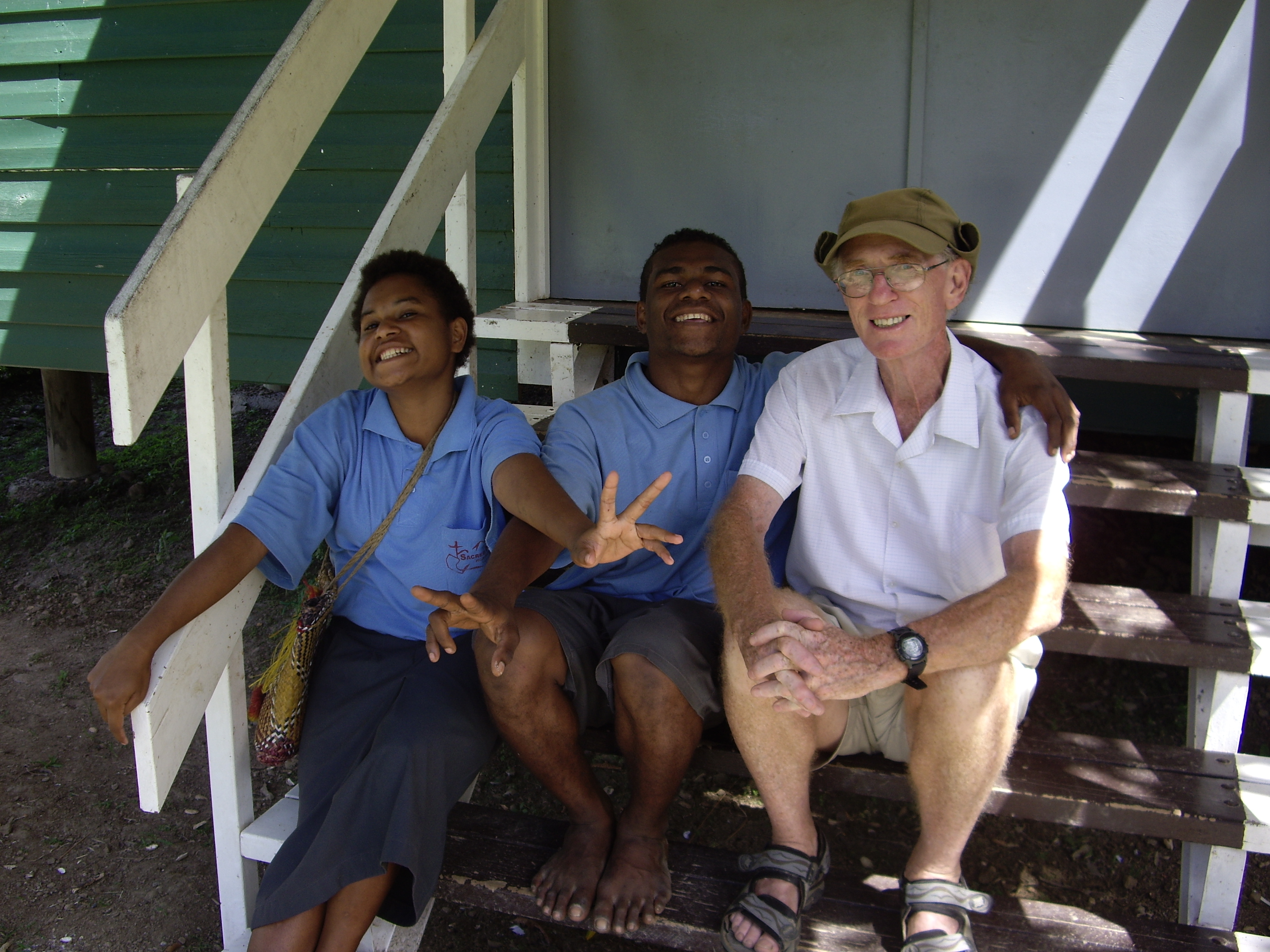 Palms Australia volunteer Des with two students on the library steps in Tapini