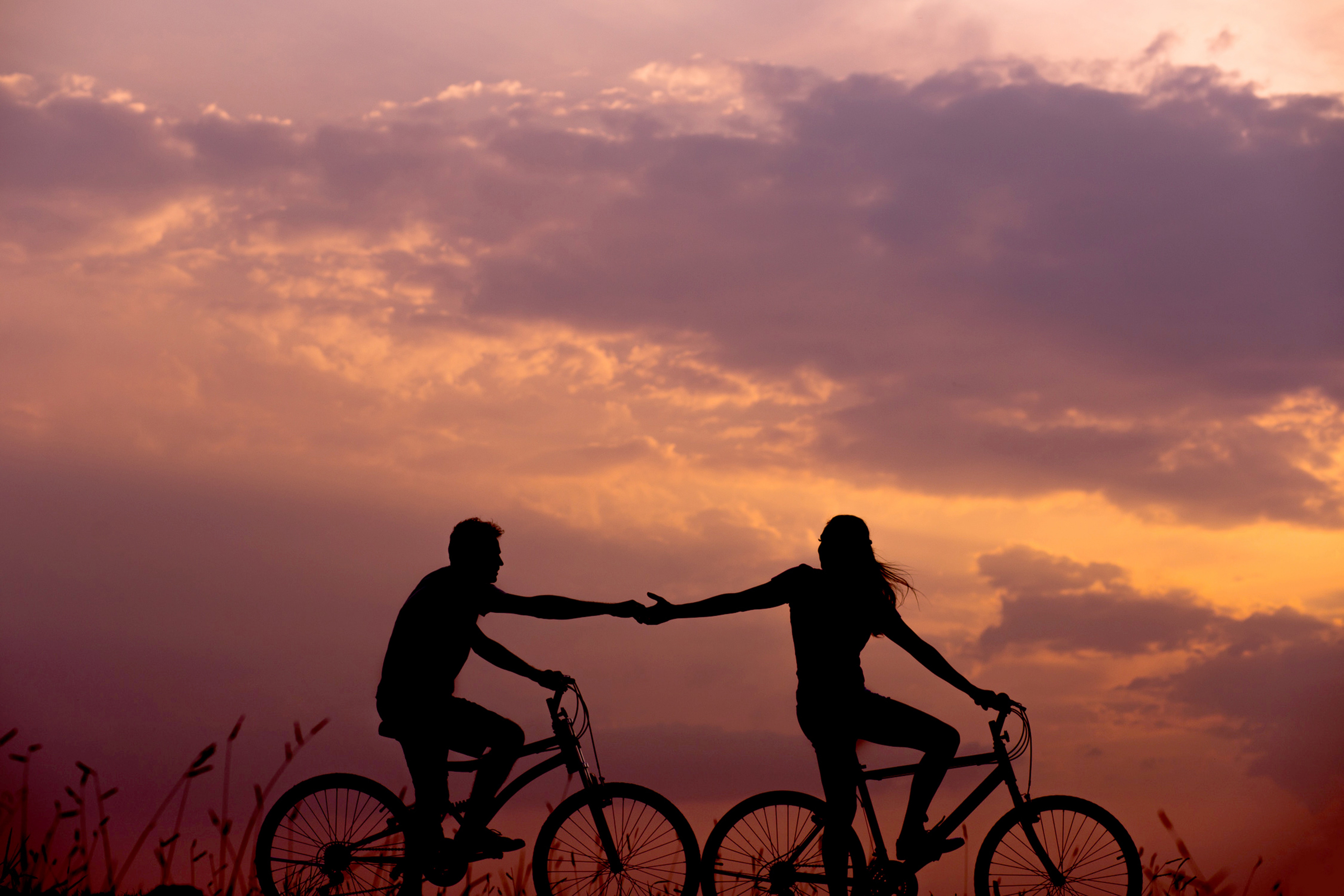 Couple holding hands riding bike