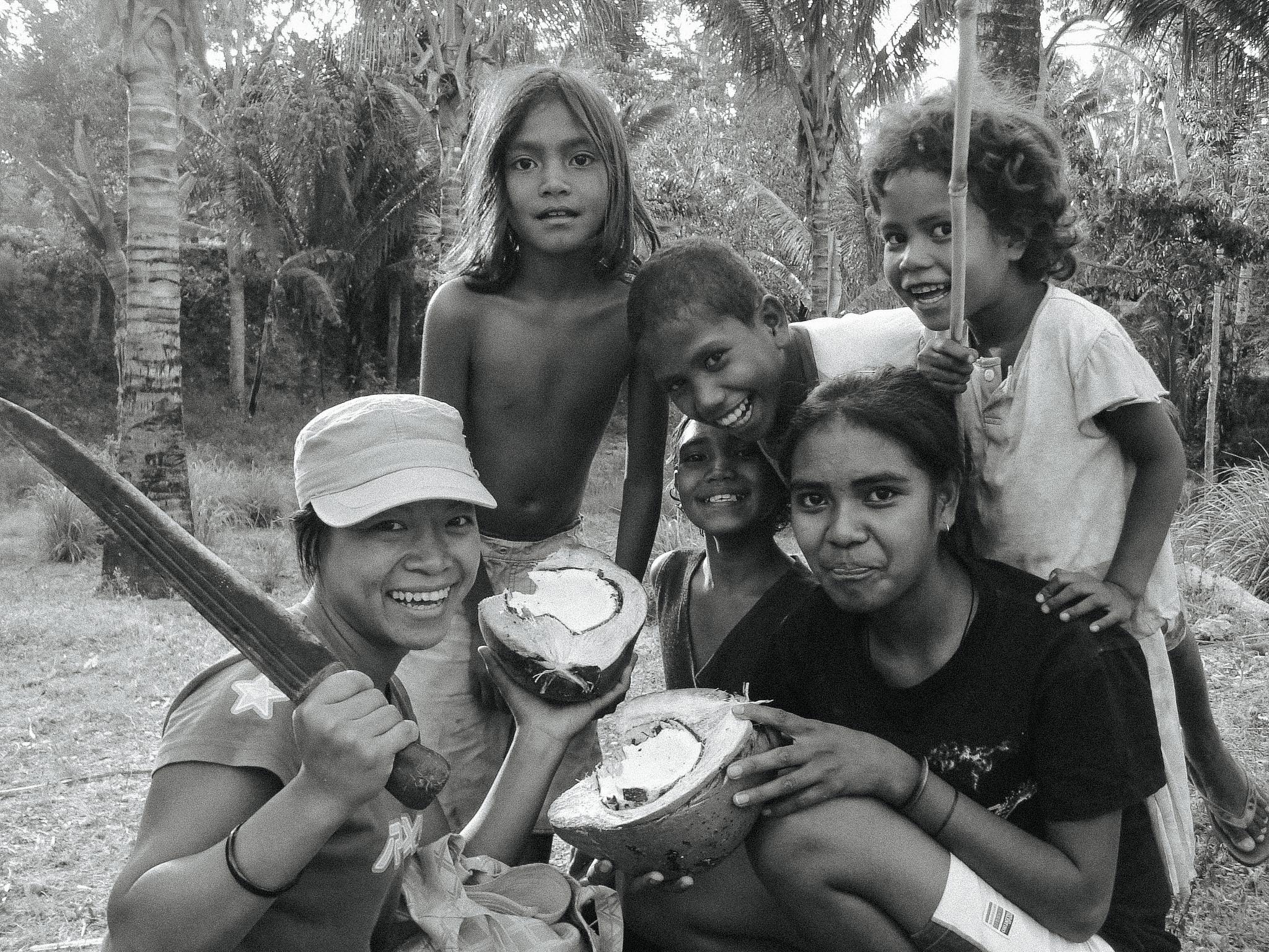 International volunteer with children in Timor-Leste holding coconuts