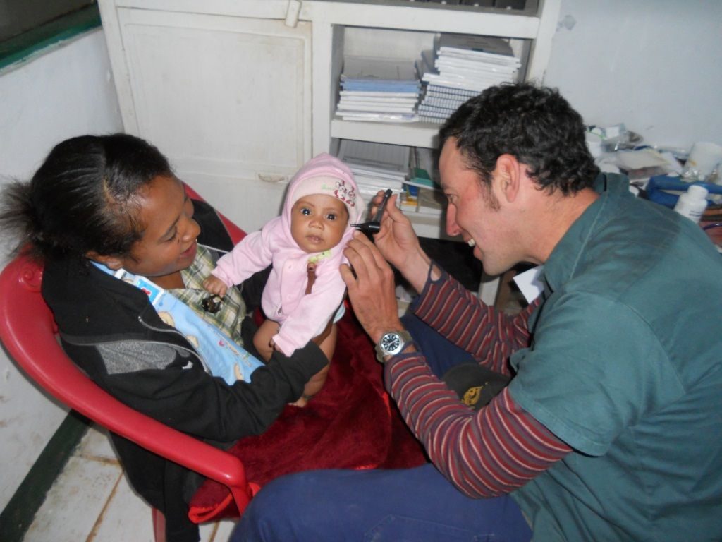 Volunteer Damien Rake with a young patient and mother at the community clinic Hatubuilico.