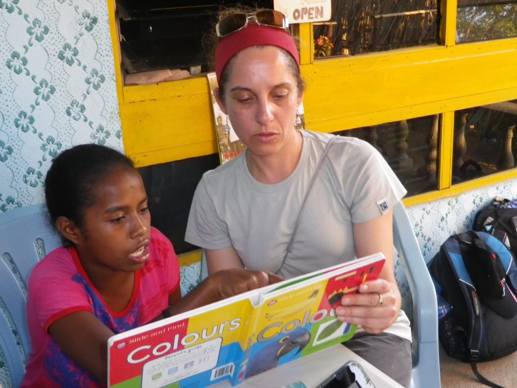 Volunteer reading a book to a child in Timor-Leste