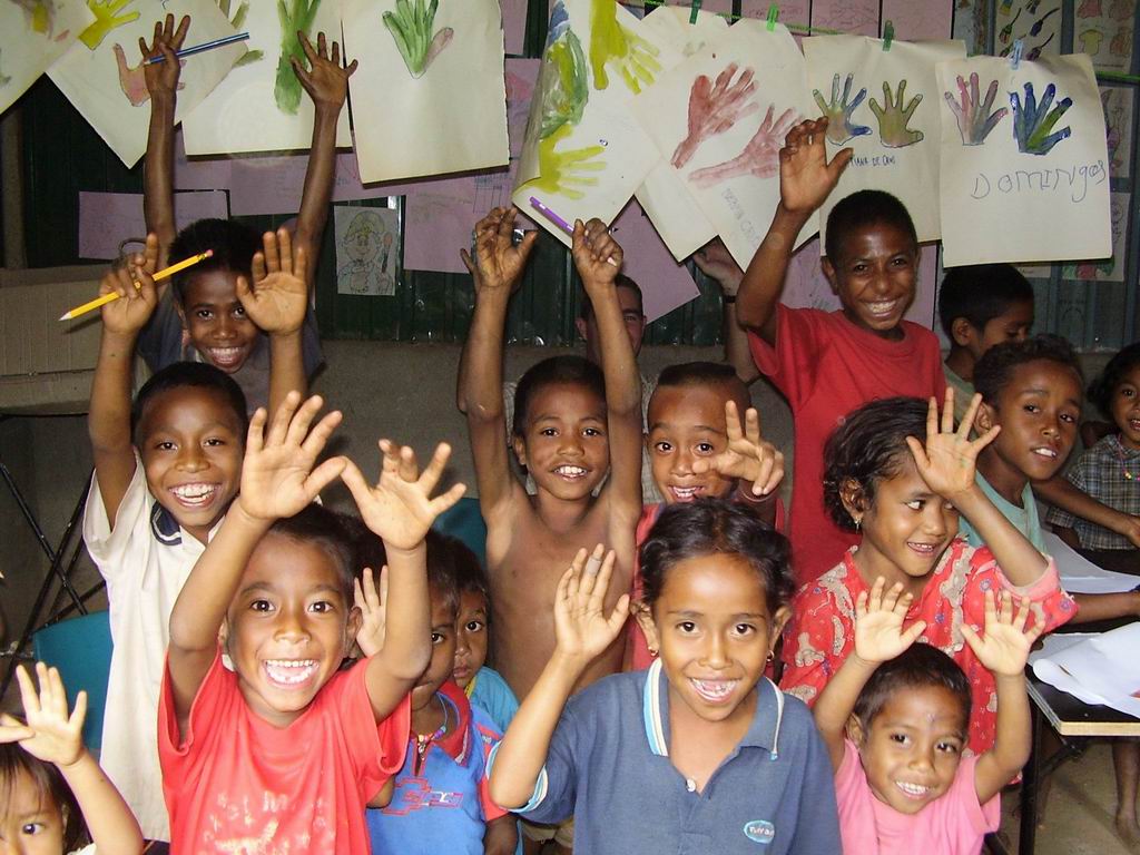 Children at Ahisaun, Timor-Leste with their hands up, smiling