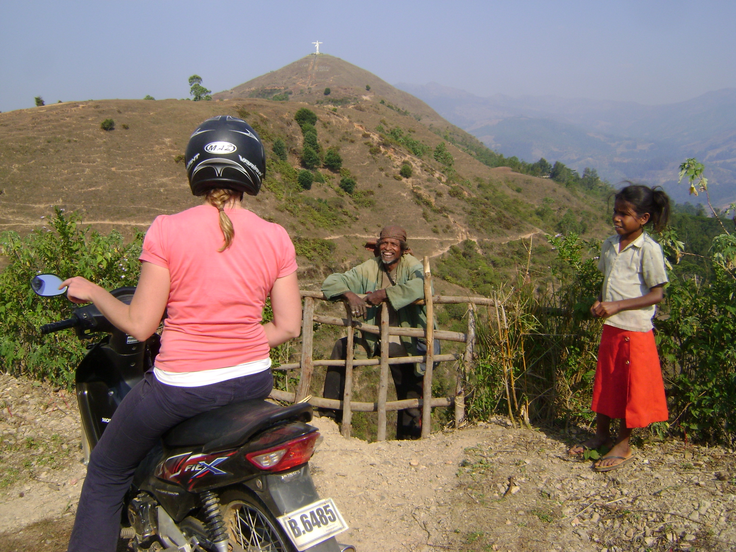 Woman on motorbike chatting with locals in Timor-Leste